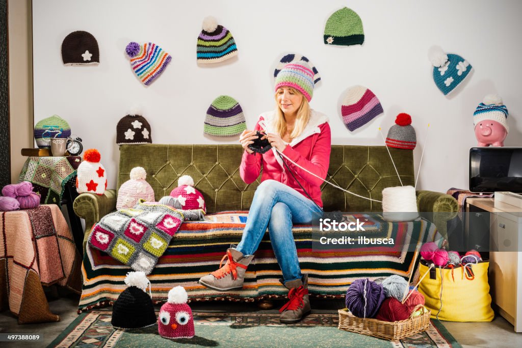 Young woman knitter portrait on couch with winter hats Knitting Stock Photo