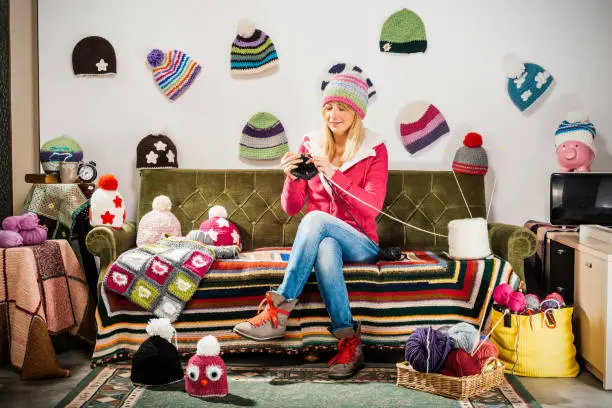 Photo of Young woman knitter portrait on couch with winter hats