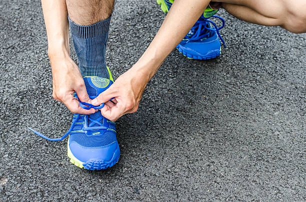 istock Male athlete tying laces for jogging on road 497390020