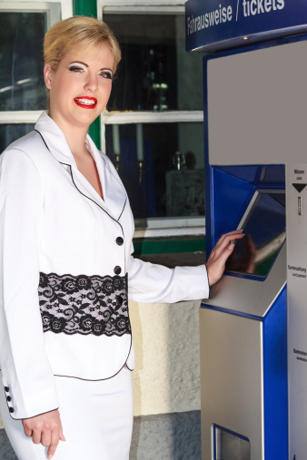 Elegant business woman wants to buy a ticket at the vending machine