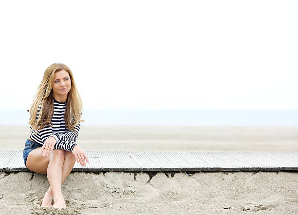 istock Young woman sitting at the beach thinking 497393761