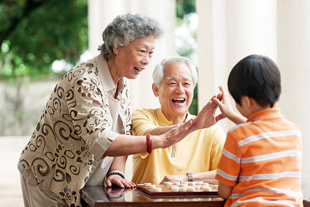 abuelo, abuela y nieto jugando xiangqi (ajedrez chino) - concentration chess playing playful fotografías e imágenes de stock