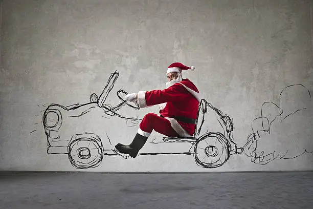 Old man dressed as santa claus driving a drawn car and looking in the camera