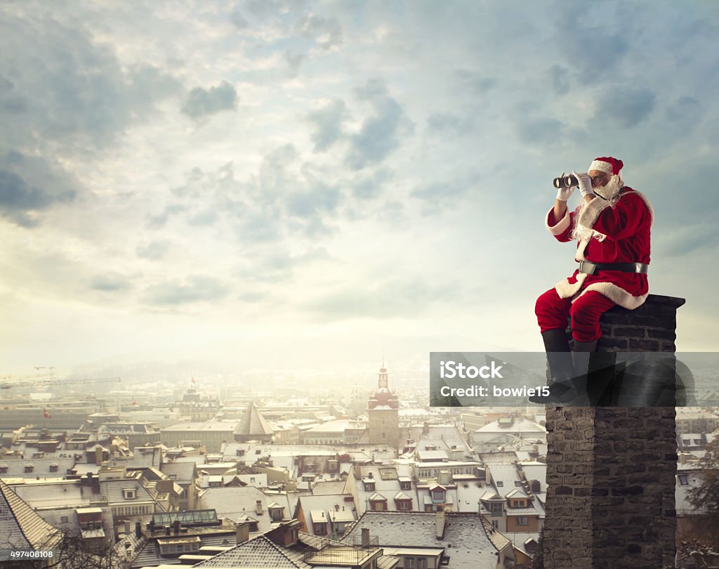 Gazing in the distance Old man dressed as santa claus searching in the distance while sitting on top of a chimney Santa Claus Stock Photo