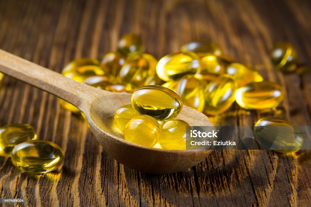 Cod-liver oil, omega3, vitamin D Cod-liver oil, omega3, vitamin D capsules on wooden spoon Vitamin D Stock Photo