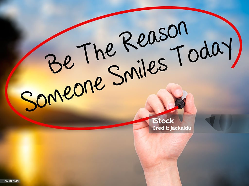 Handwriting Be The Reason Someone Smiles Today Man Hand writing Be The Reason Someone Smiles Today with black marker on visual screen. Isolated on nature. Business, technology, internet concept. Motivation Stock Photo
