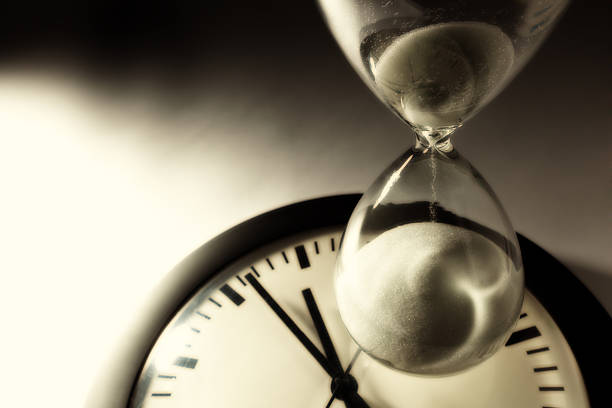 An hourglass and a clock for deadline and the passage of time