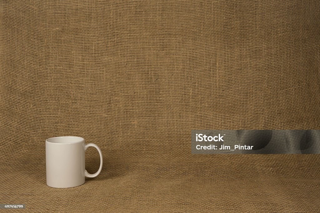 Coffee Mug Background - White Mug Coffee Mug Background.  Photograph showing a white coffee mug lower left and in front of a natural burlap background.  There’s ample copy space in the frame.  This image could be applicable to many concepts including coffee breaks, business meetings, PowerPoint presentations, food and drink, relaxation, dining out, and many more. Black Color Stock Photo