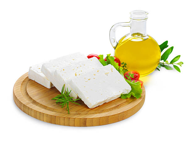 feta cheese slices on wood feta cheese(Greek cheese) slices on a wooden serving board decorated with fresh vegetables and a bottle of olive oil white cheese stock pictures, royalty-free photos & images