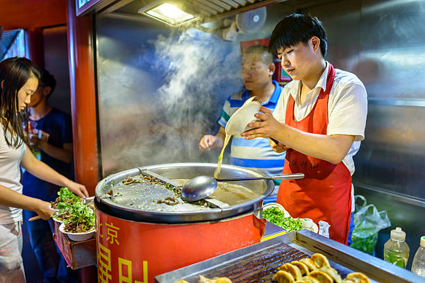 Wangfujing Snack Street Beijing, China -  August 18, 2015: Wangfujing Snack Street at night. Chinese chef selling Ancient Beijing Soiled Pork Tripe. Located in Beijing, China. wangfujing stock pictures, royalty-free photos & images