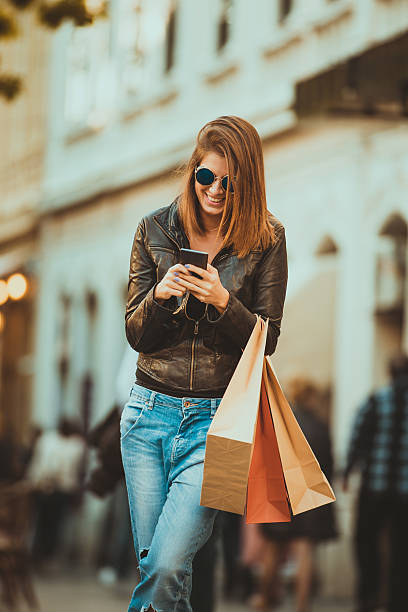 istock Woman with shopping bags using her mobile phone 497423162