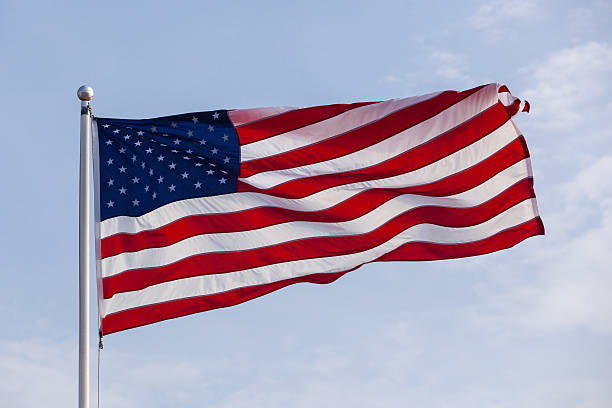 istock American Flag Blowing in Wind on Blue Sky 497434003