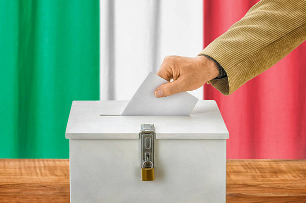 istock Man putting a ballot into a voting box - Italy 497437764