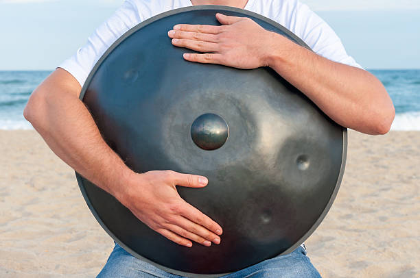 Busker hold the Hang or handpan with sea on background