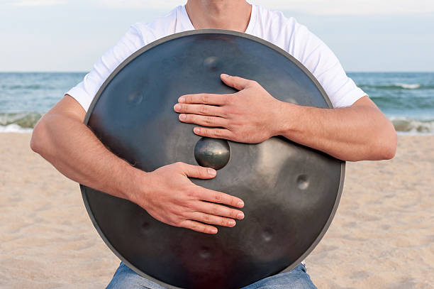istock Busker hold the Hang or handpan with sea on background 497438448