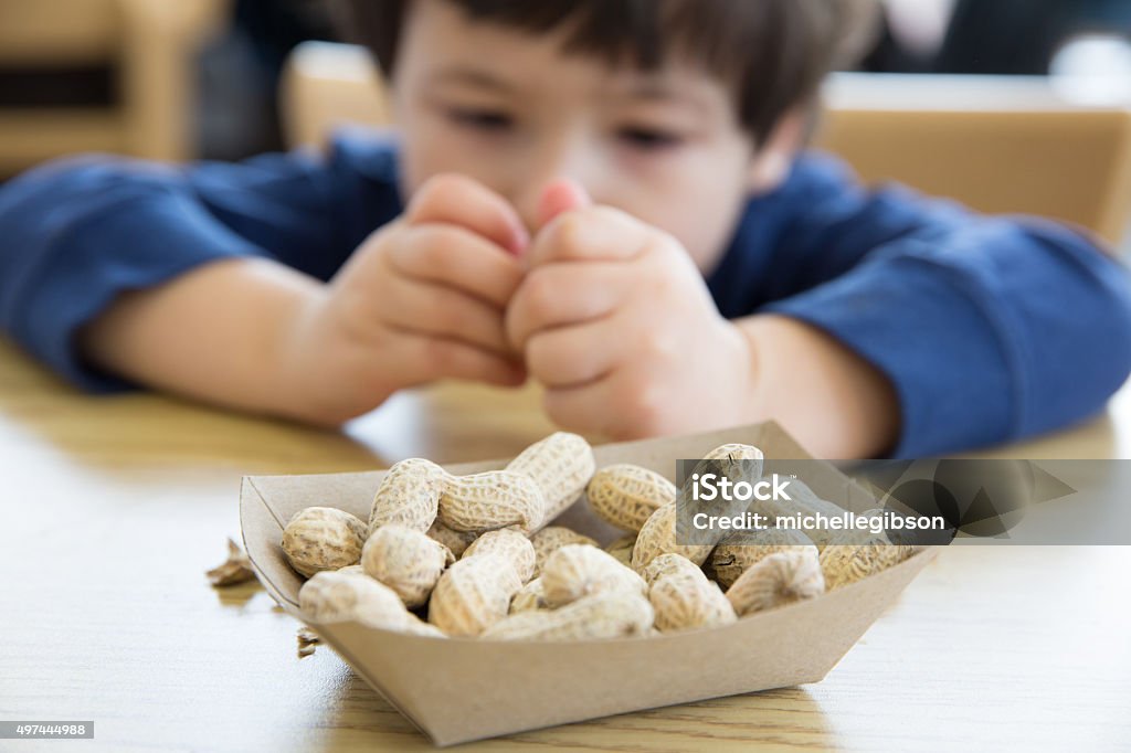 Little boy eating peanuts Little boy opening up peanuts to eat in a restaurant Allergy Stock Photo