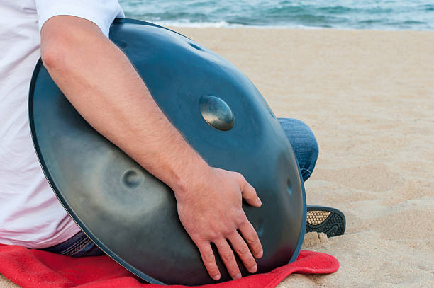 istock Busker hold the Hang or handpan with sea on background 497446152