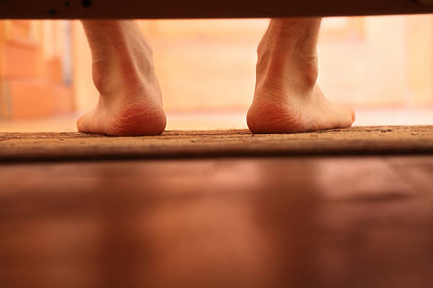 male bare feet photo from under the bed, selective focus