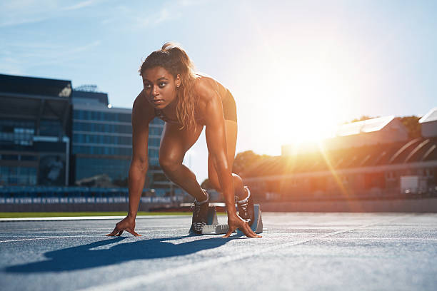 mujer a punto de iniciar una carrera de velocidad - atleta papel social fotografías e imágenes de stock