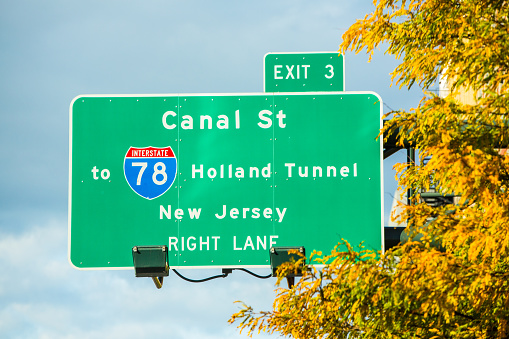 Sign in Manhattan for exit for Canal Street and the Holland Tunnel. The Holland Tunnel connects Manhattan to New Jersey. It goes under Hudson River. The leaves on the trees show that it is autumn, with their yellow and orange vibrant colors.  Taken with a Canon 5D Mark 3.  Rm