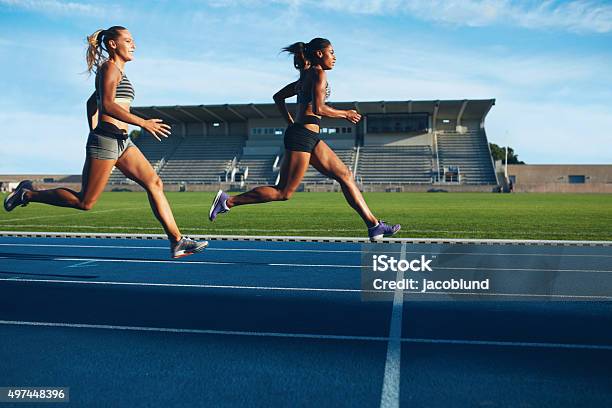 Atletas Llega En Línea De Meta En La Pista De Carreras Foto de stock y más banco de imágenes de Correr