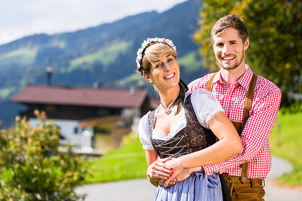 paar in tracht stehend auf wiese in alpen berge - österreich tracht stock-fotos und bilder