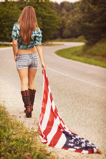 Independence day Beautiful young woman walking with american flag larrikin stock pictures, royalty-free photos & images