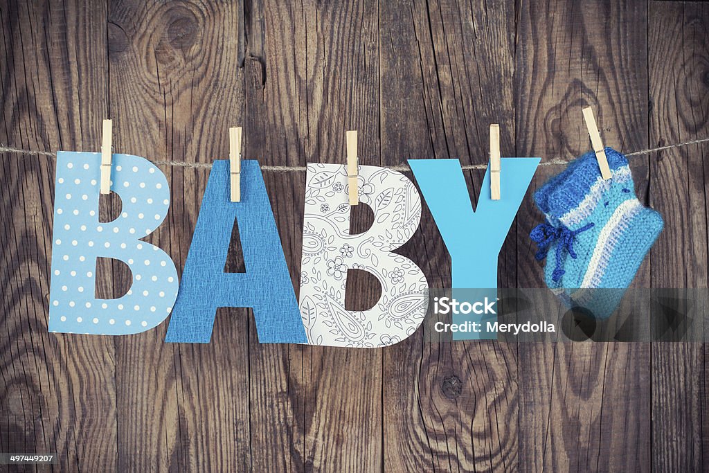 letters of word baby letters of word baby and knitted socks hanging on clothesline against wooden background Blue Stock Photo