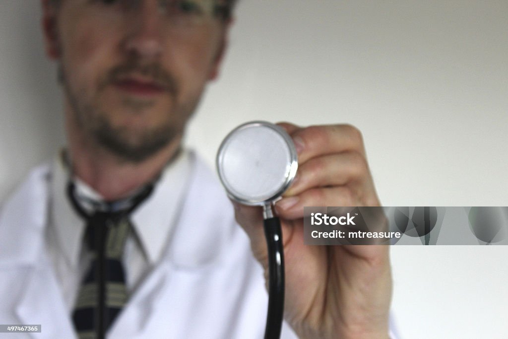 Image of hospital doctor's stethoscope, with blurred doctor in background Photo showing a hospital doctor's stethoscope, pictured in focus in the foreground, with the blurred doctor looking on in the background as he holds it up. Accidents and Disasters Stock Photo