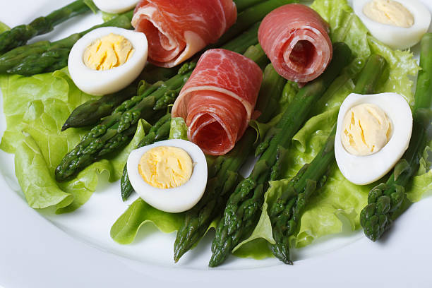 Boiled quail eggs with ham and asparagus close-up top view Boiled quail eggs with ham and asparagus on a plate close-up view from above. asparagus organic dinner close to stock pictures, royalty-free photos & images