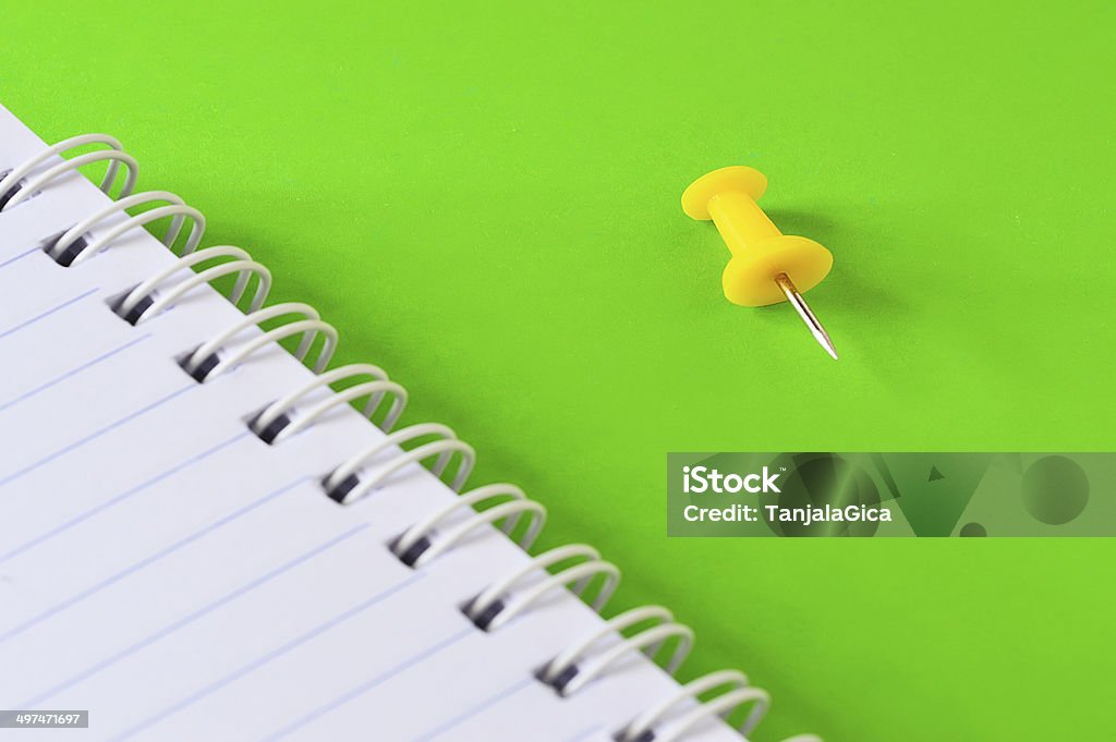 agenda and yellow push pin isolated on green background Attached Stock Photo