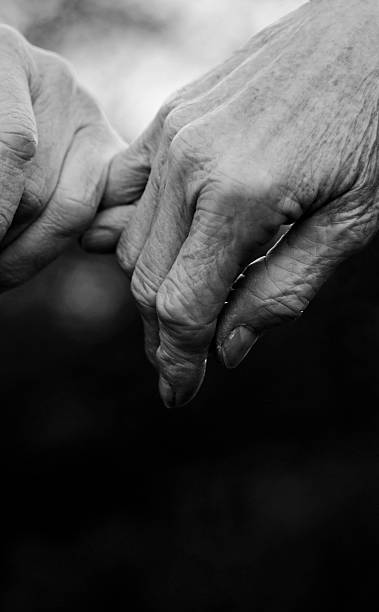 istock Senior married couple reaching for each other's hands closeup 497483406