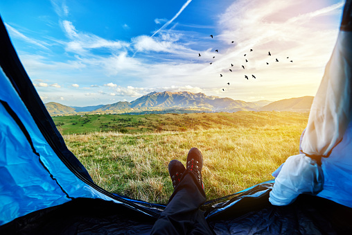 man legs inside tent, lying down and relaxing in his mountain adventure.personal perspective inside the tent.