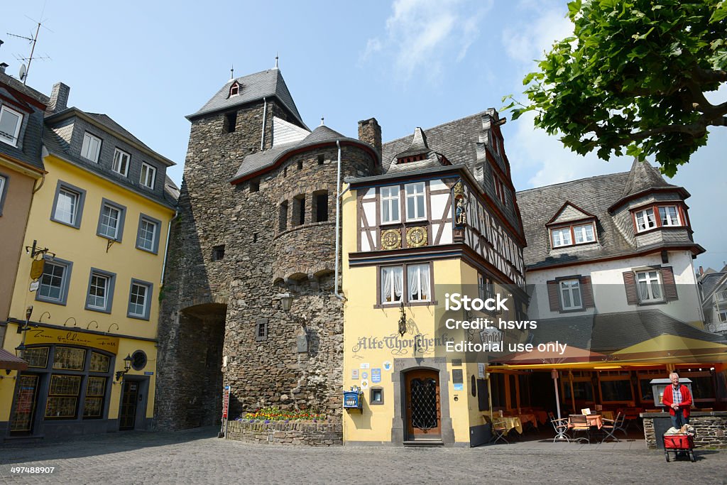 Old city gate of Cochem (Germany) Cochem, Germany - June 2, 2014: Old city gate of Cochem (Mosel Valley, Germany). It is surrounded by small wine bars and half-timbered houses. A man standing with his dog on the site. Wine Bar Stock Photo