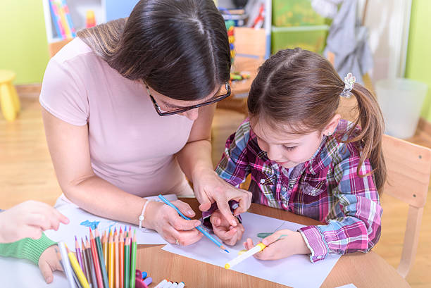 istock Kindergarten Teacher Helping Child in Creative Activities 497490448