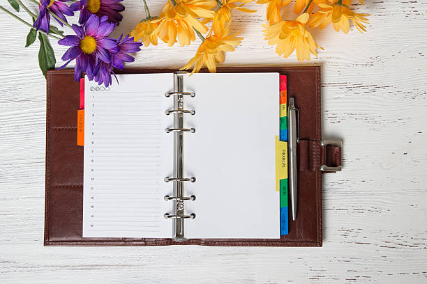 istock Day planner and flowers on the wood table. 497492727