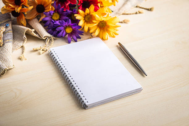 istock Notepad,pencil and flowers on wood table. 497493783