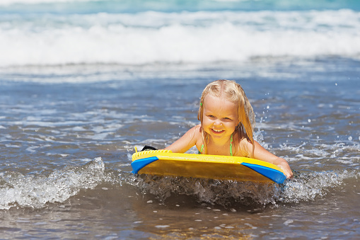 Little child swimming with bodyboard on the sea waves
