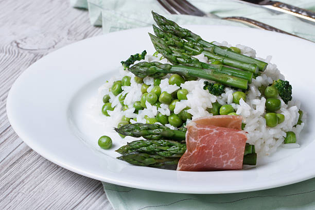 risotto with asparagus and green peas close-up risotto with asparagus and green peas close-up on a plate. horizontal. asparagus organic dinner close to stock pictures, royalty-free photos & images