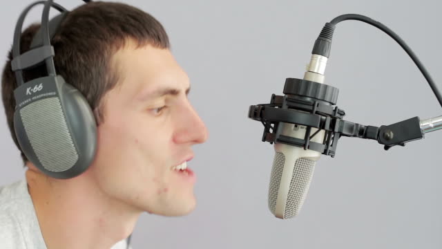 Man in headphones singing at studio microphone