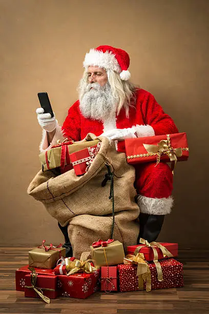 Photo of santa claus with many gifts and a phone
