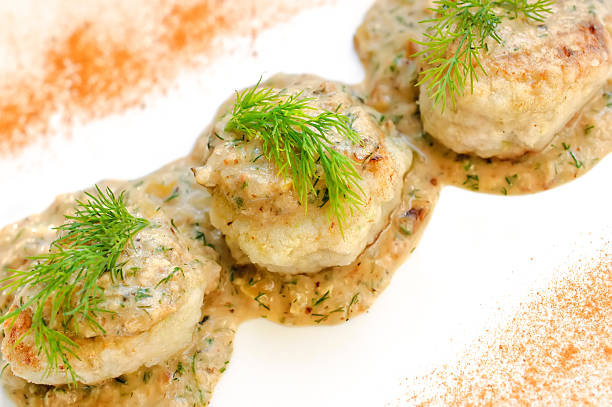 Meatballs served in a dill sauce on a white plate.