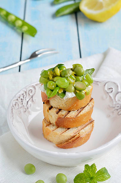 Toasted bread topped  (Bruschetta) with green peas and ricotta cheese stock photo