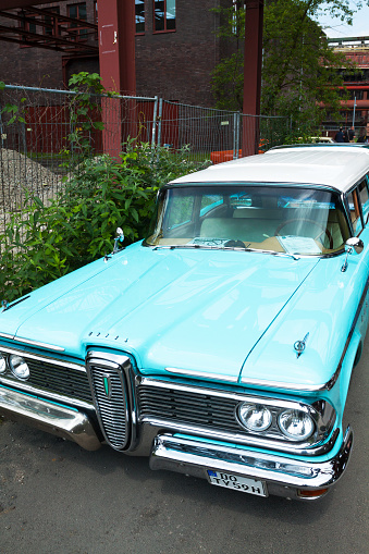 Essen, Germany - June 1, 2014: Cyan Ford Edsel oldtimer standing on grounds of Zeche Zollverein in summer. Public and private oldtimer meeting for showing private collector's cars. In window is sign for not touching. In backgrund are some people watching other cars.
