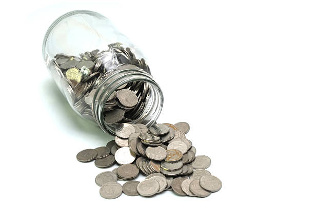 istock Jar of thai coins spilled on a white background 497516954