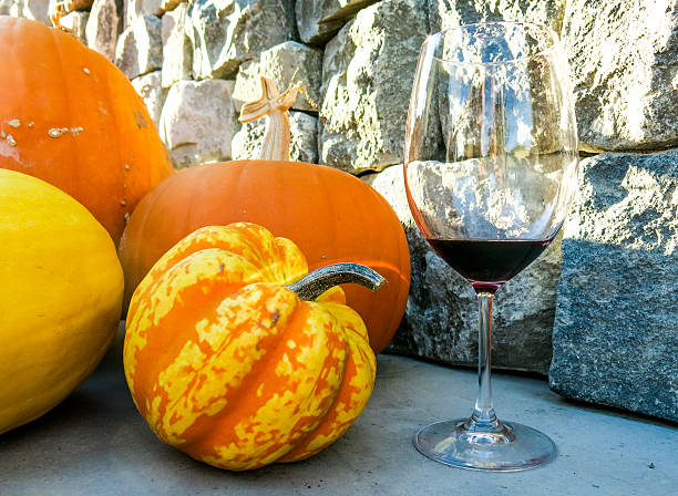 Glass of red wine next to bright orange pumpkins stock photo