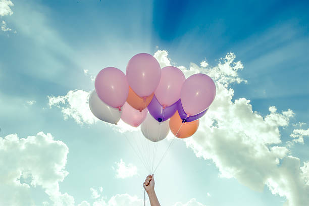 istock hand holding colorful balloons on blue sky background 497522798