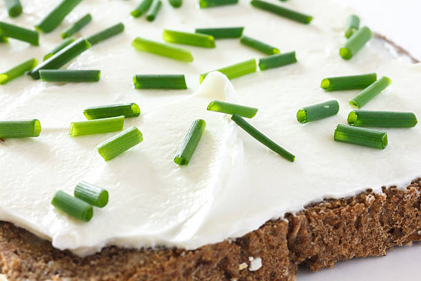 Dark bread with chives on thickly spread cream cheese .