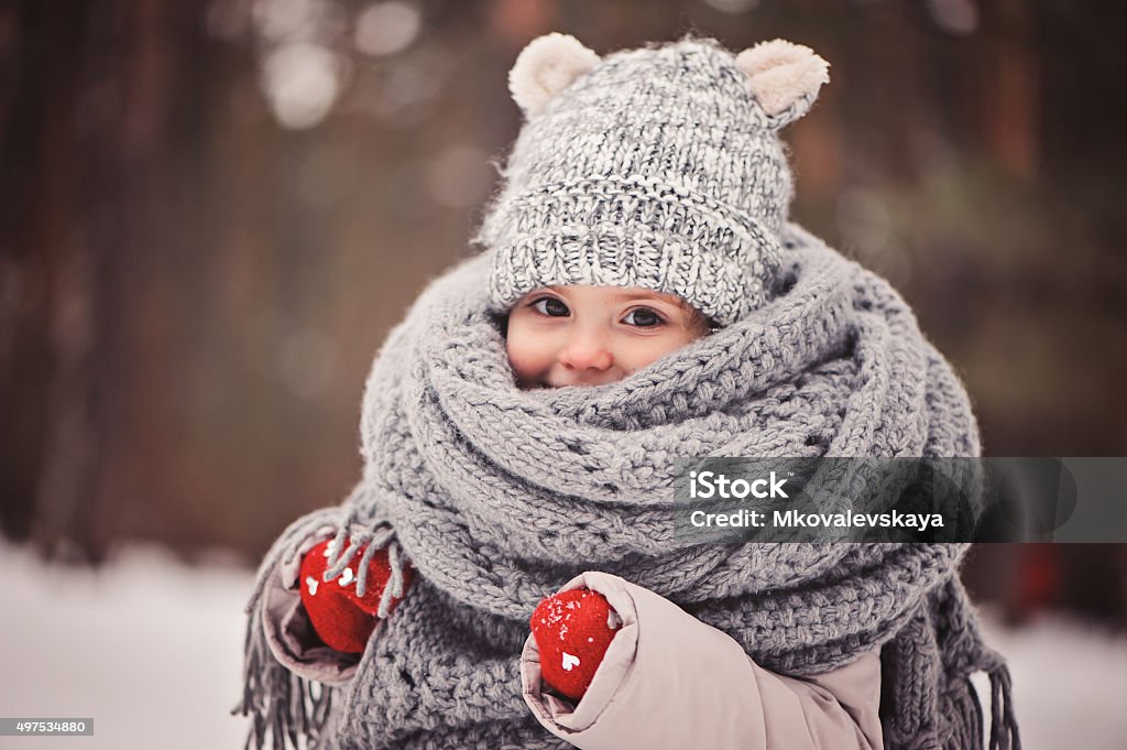 cozy outdoor portrait of happy toddler child girl in winter dreamy cozy outdoor portrait of toddler child girl in winter, wearing red gloves, grey knitted hat and scarf Child Stock Photo
