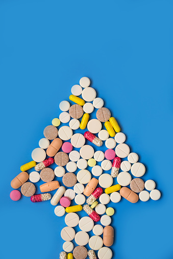 Closeup of an arrow made of tablets on a blue background. Medical direction signal. Top view.
